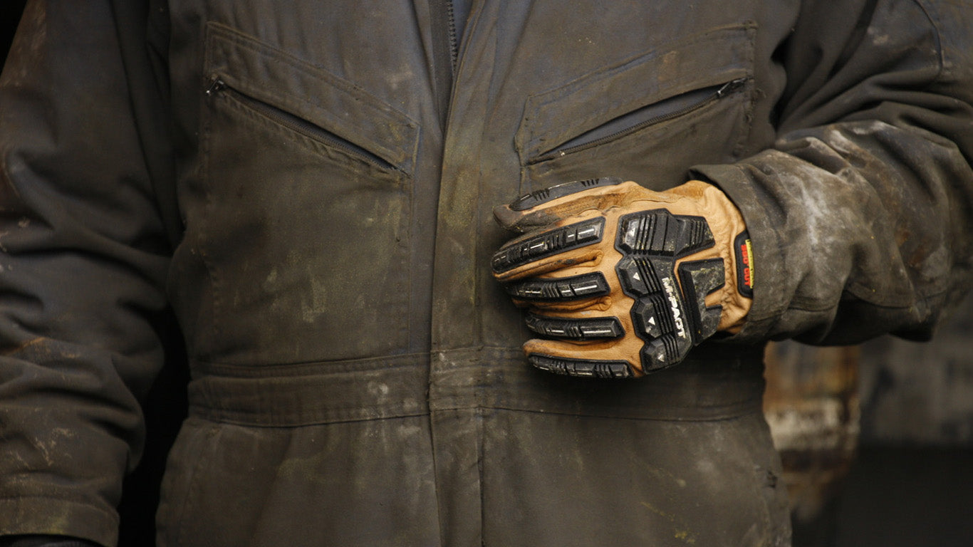 worker wearing mechanix wear m-pact driver f9-360 cut resistant gloves in brown leather with black tpr knuckle protection standing in work overalls