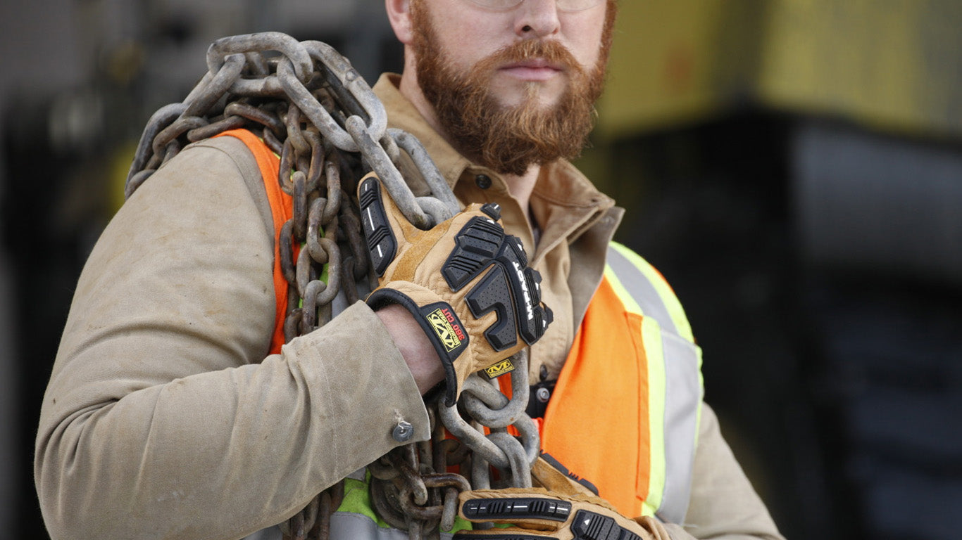 construction worker carrying heavy steel chains while wearing mechanix wear m-pact driver f9-360 cut resistant gloves in brown leather with black impact guards